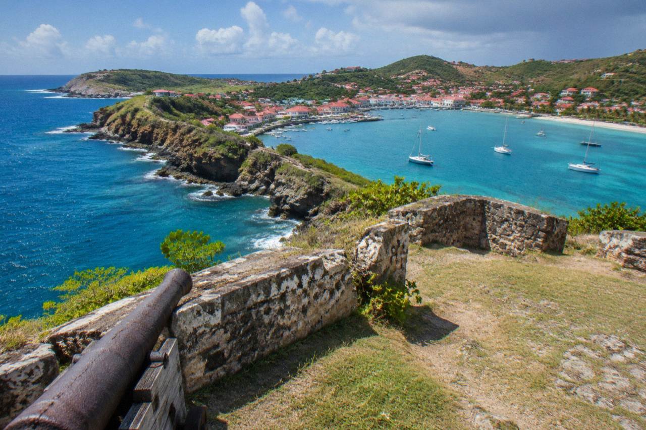 Red-roofed houses above a Caribbean harbour with green hills and turquoise water
