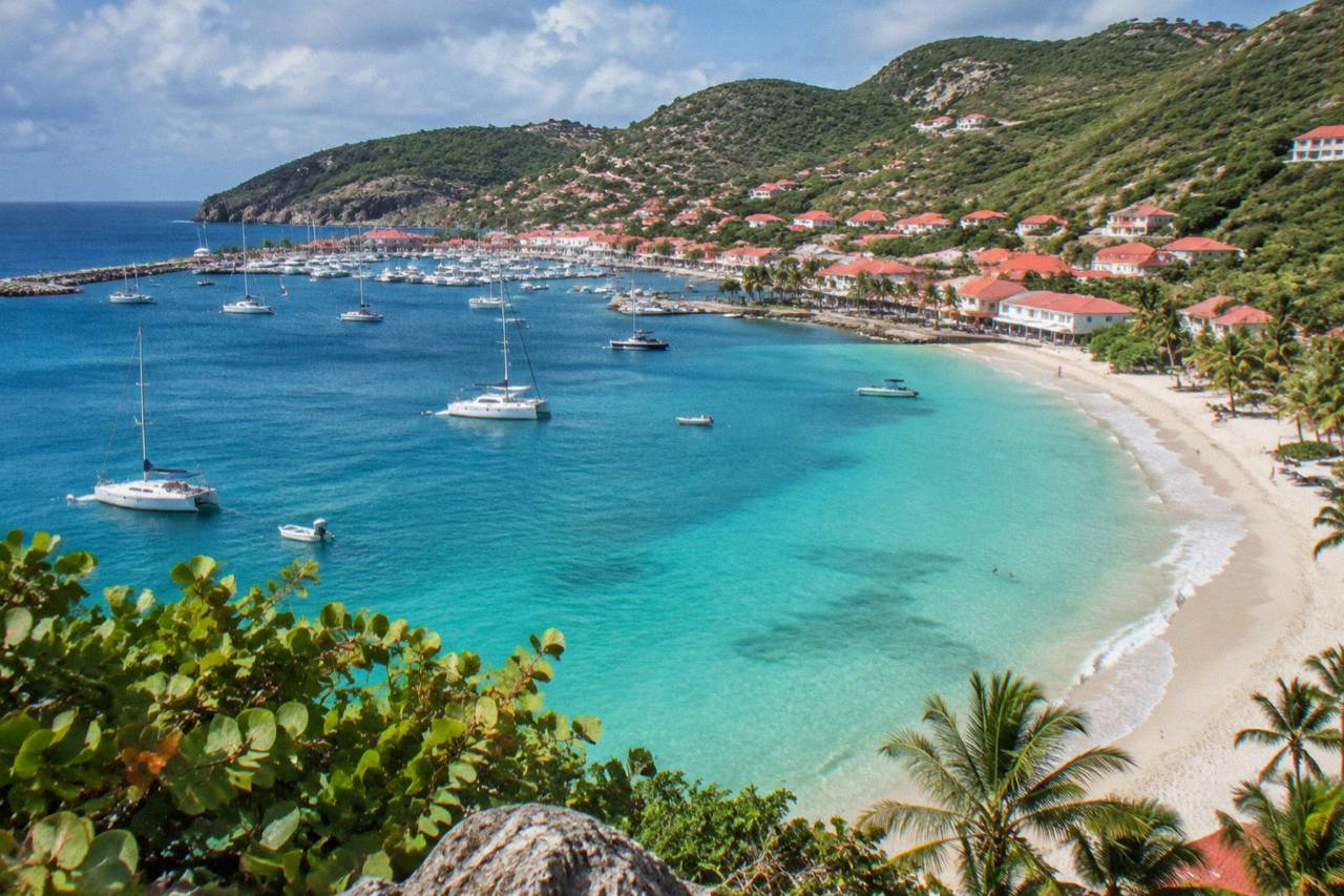 A quiet crescent beach with turquoise water and green hills on St Barts