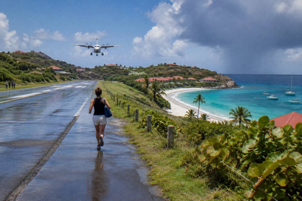 A small turboprop aircraft on a short runway beside a beach and hills