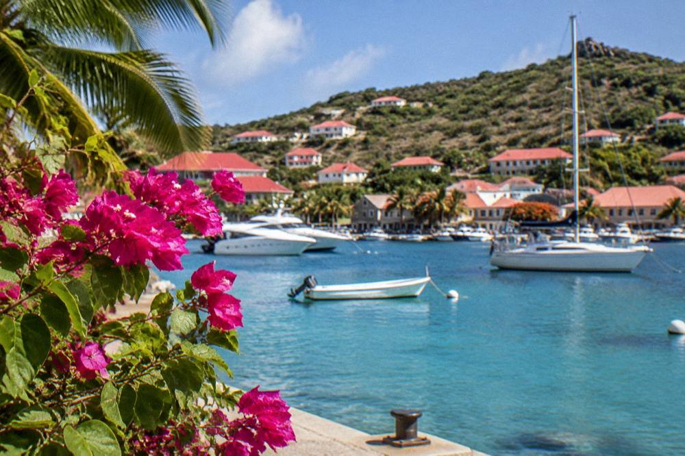 Red-roofed houses around a small Caribbean harbor with yachts at anchor