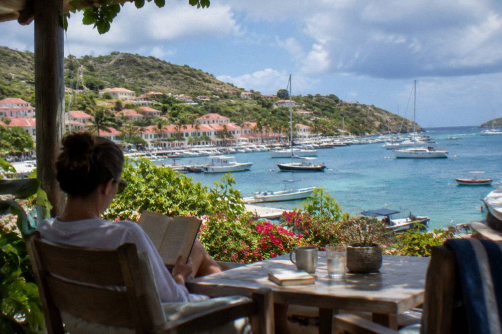 Travelers reading on a shaded terrace overlooking the Caribbean sea