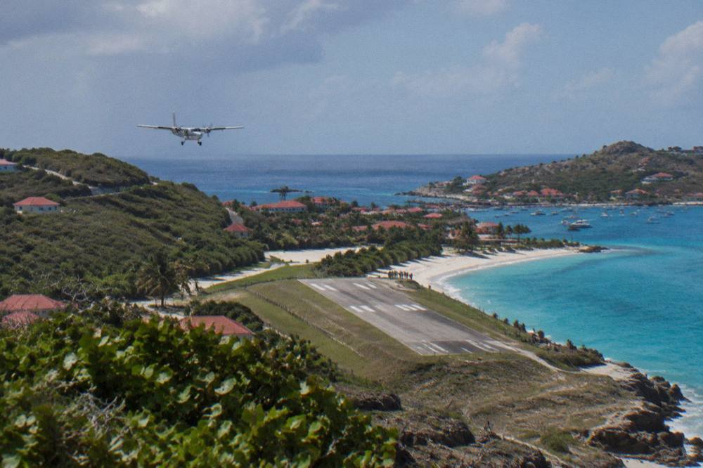 A small turboprop aircraft on a short runway beside a beach