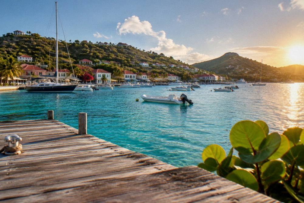 A wooden dock extending into clear turquoise water at sunset