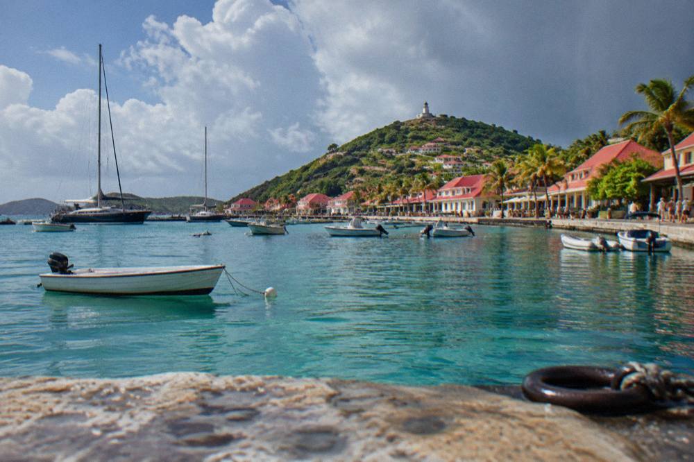A calendar and weather map on a table beside a window overlooking a Caribbean bay