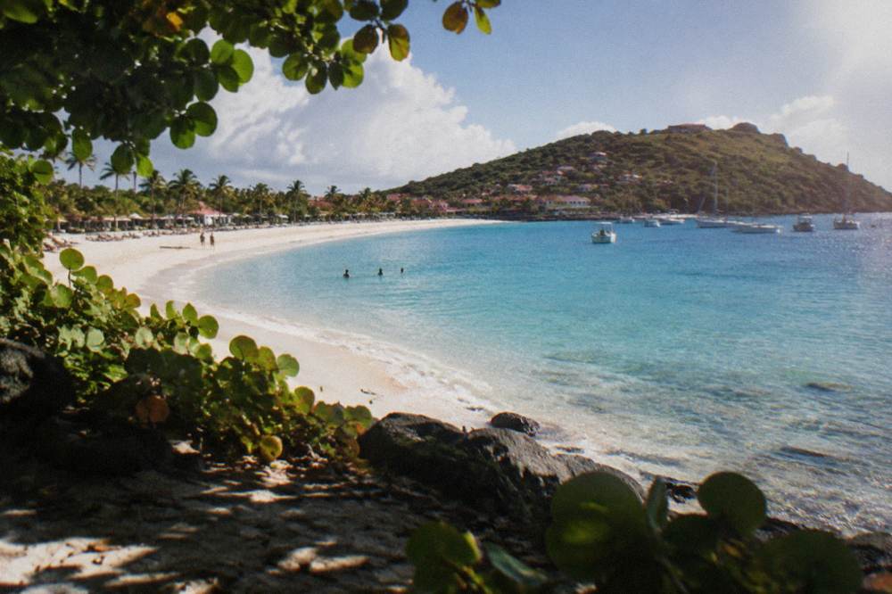 An empty crescent of white sand between green headlands and clear water