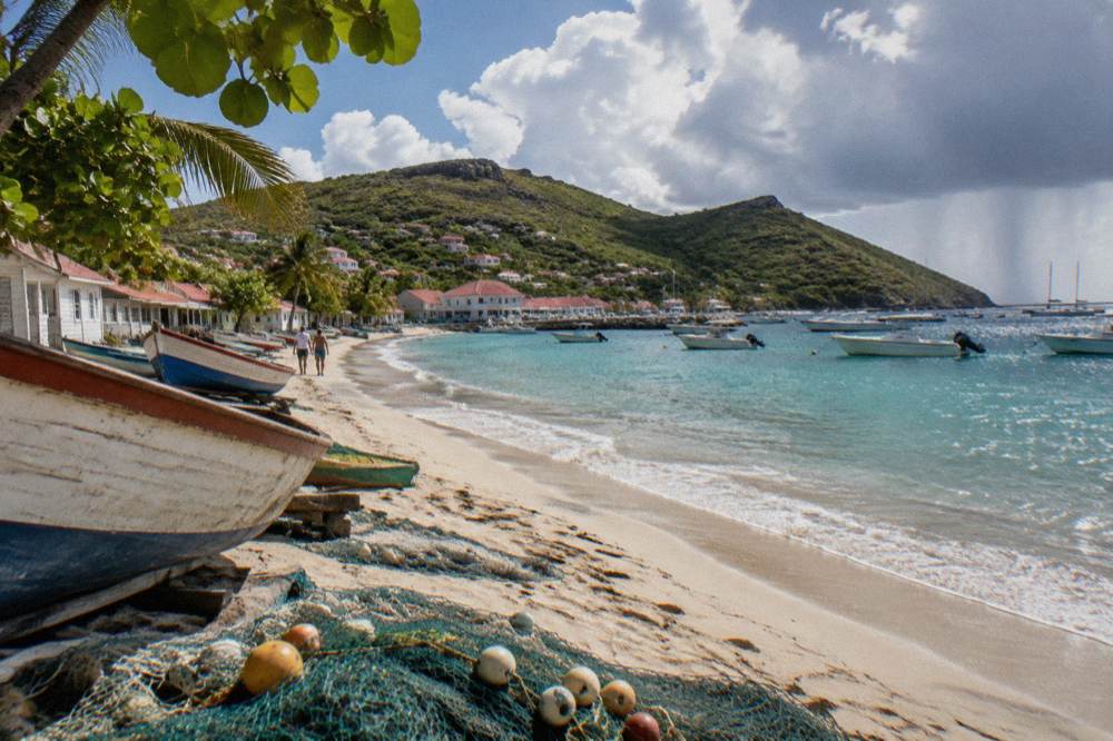 A small turboprop aircraft on a short Caribbean airstrip between a hill and a beach