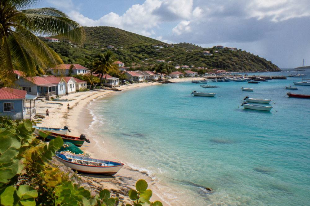 An empty crescent of pale sand and clear shallow water on a calm Caribbean morning