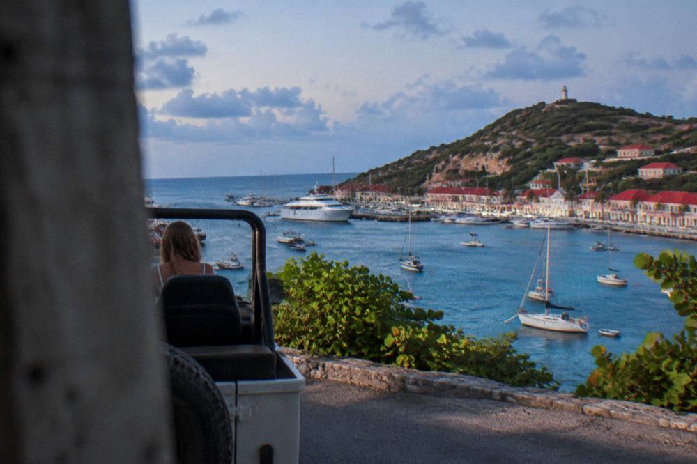 An open-air vehicle parked on a hillside road above the sea