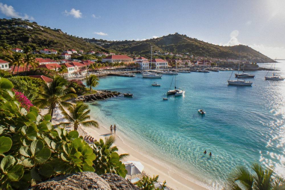 A quiet crescent of white sand and clear shallow water on a St Barts beach in morning light