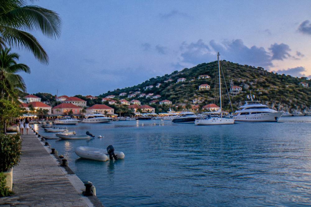White yachts anchored in Gustavia harbour with red roofs climbing the hillside behind