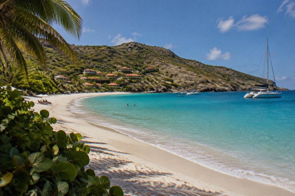 A sailing catamaran moored in a rocky bay with clear water and dry hillsides