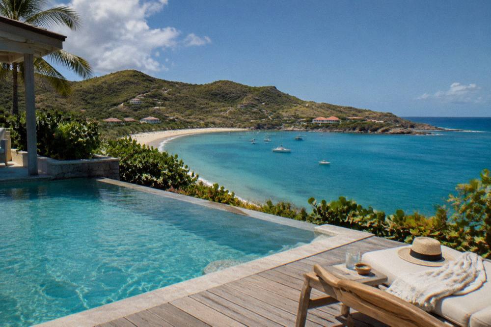A hillside villa with a terrace pool overlooking the Caribbean sea at midday
