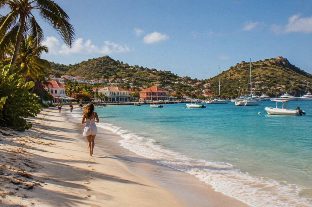 A quiet white sand beach with gentle waves and green headland in St Barts