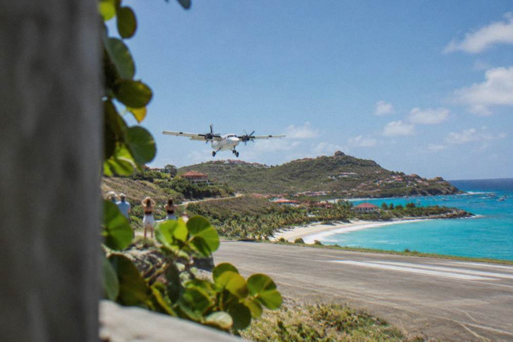 A small turboprop aircraft on the short runway at St Barts airport beside the beach