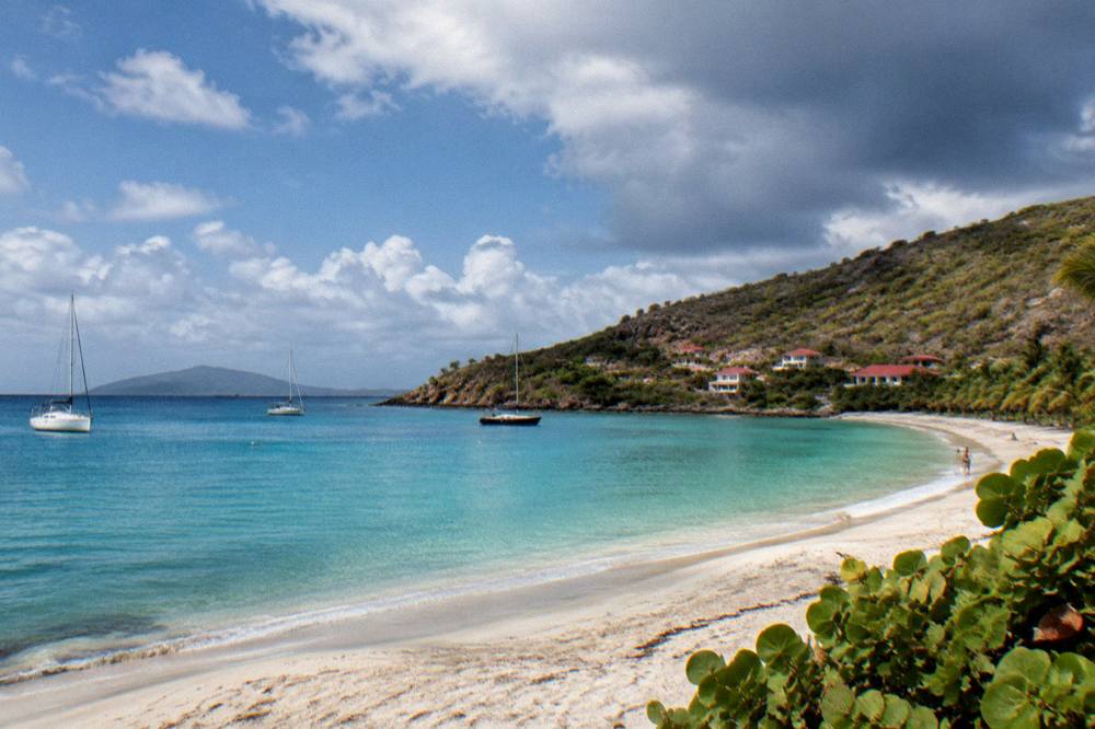 Dark clouds over a calm Caribbean sea with a distant island on the horizon