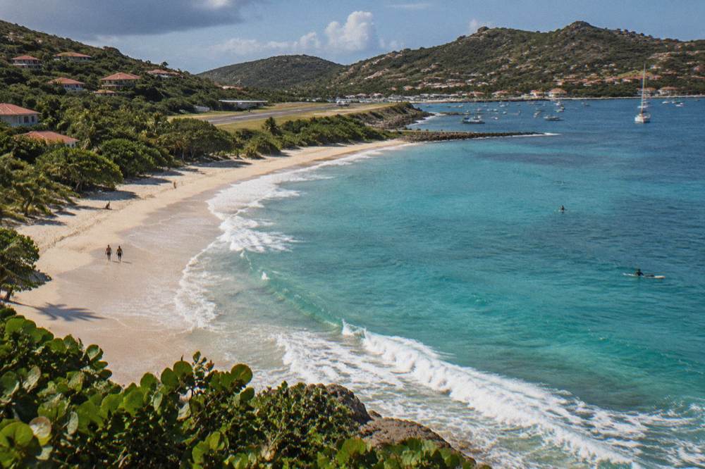 A small turboprop aircraft on a short Caribbean runway between hills and the sea