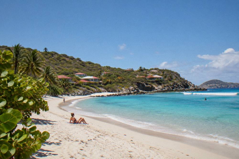 A quiet white sand beach with rocky headlands and clear shallow water