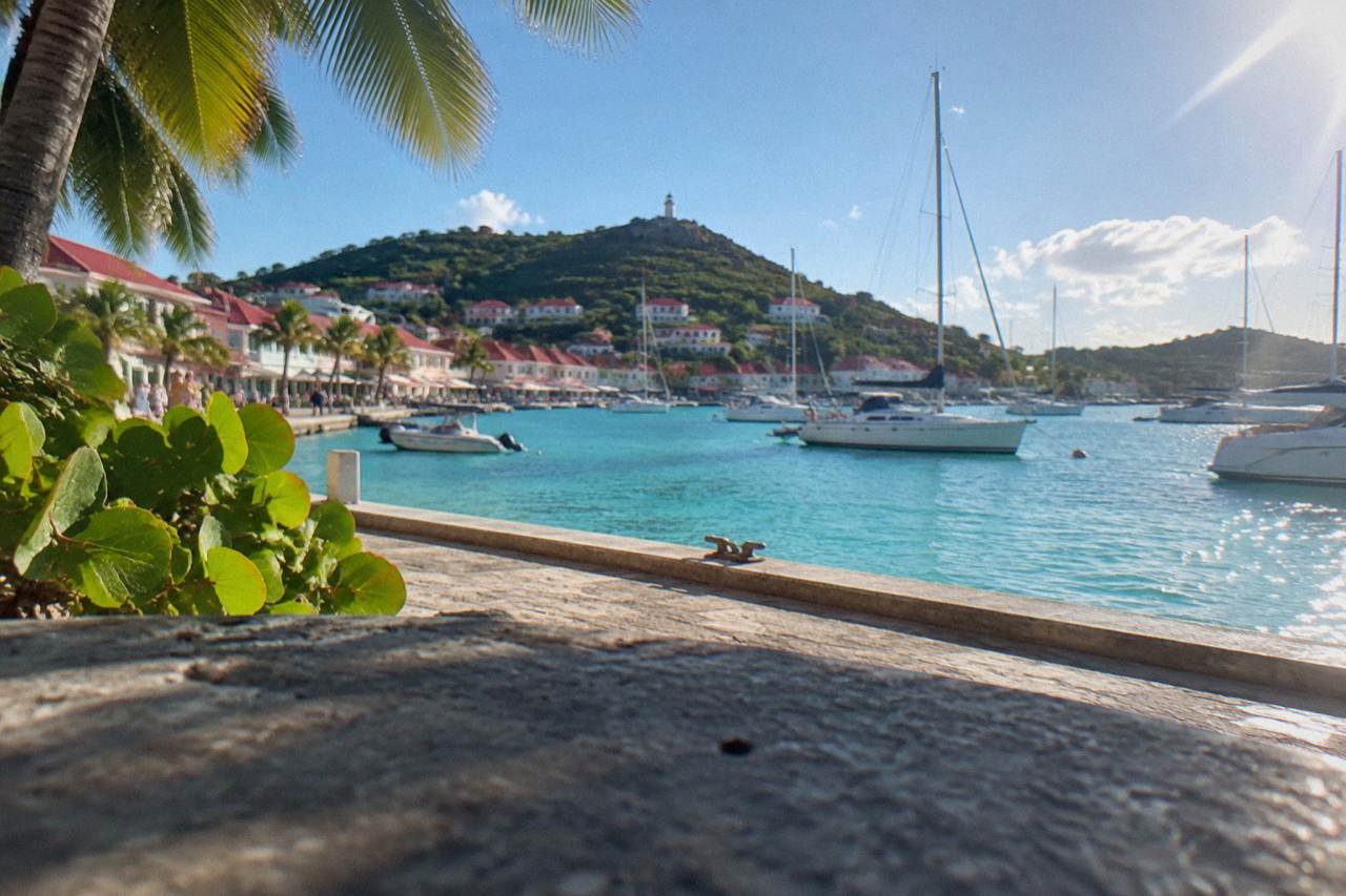 Sailboats anchored in turquoise water below green hills on a Caribbean island
