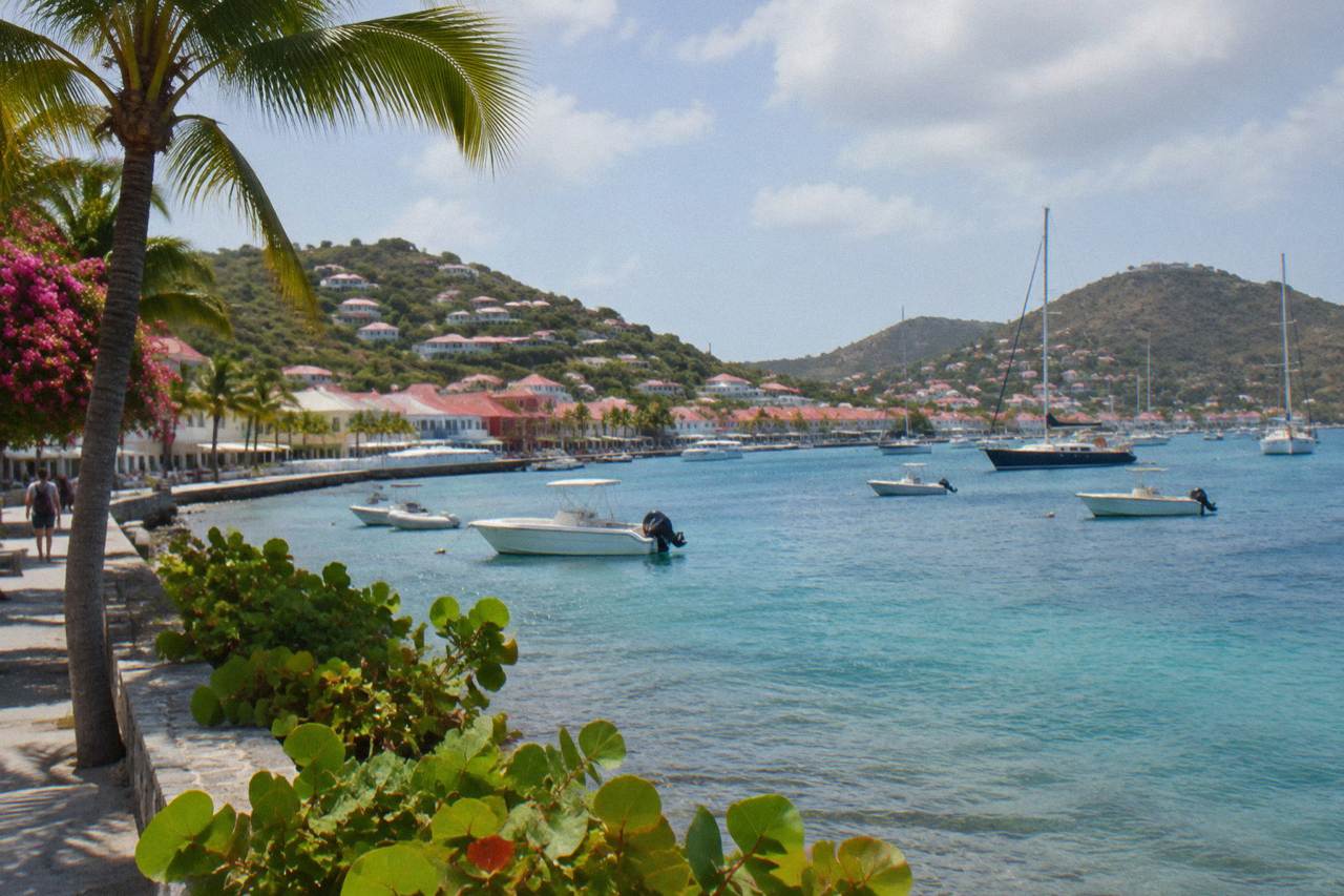 A calm Caribbean bay on St Barts with turquoise water and green hills under a partly cloudy sky