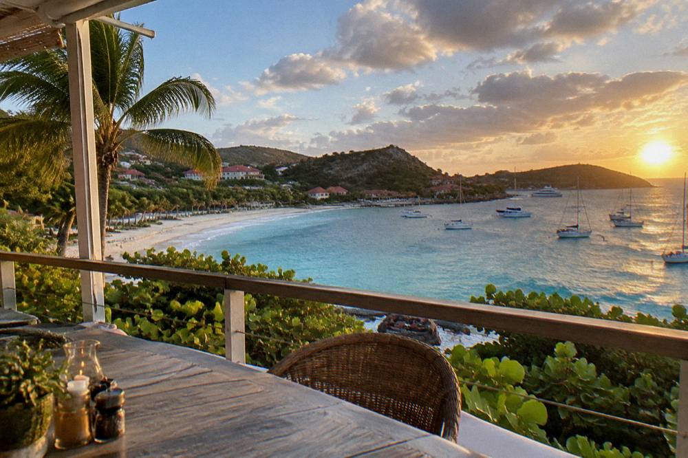 An open-air terrace overlooking a Caribbean bay at golden hour