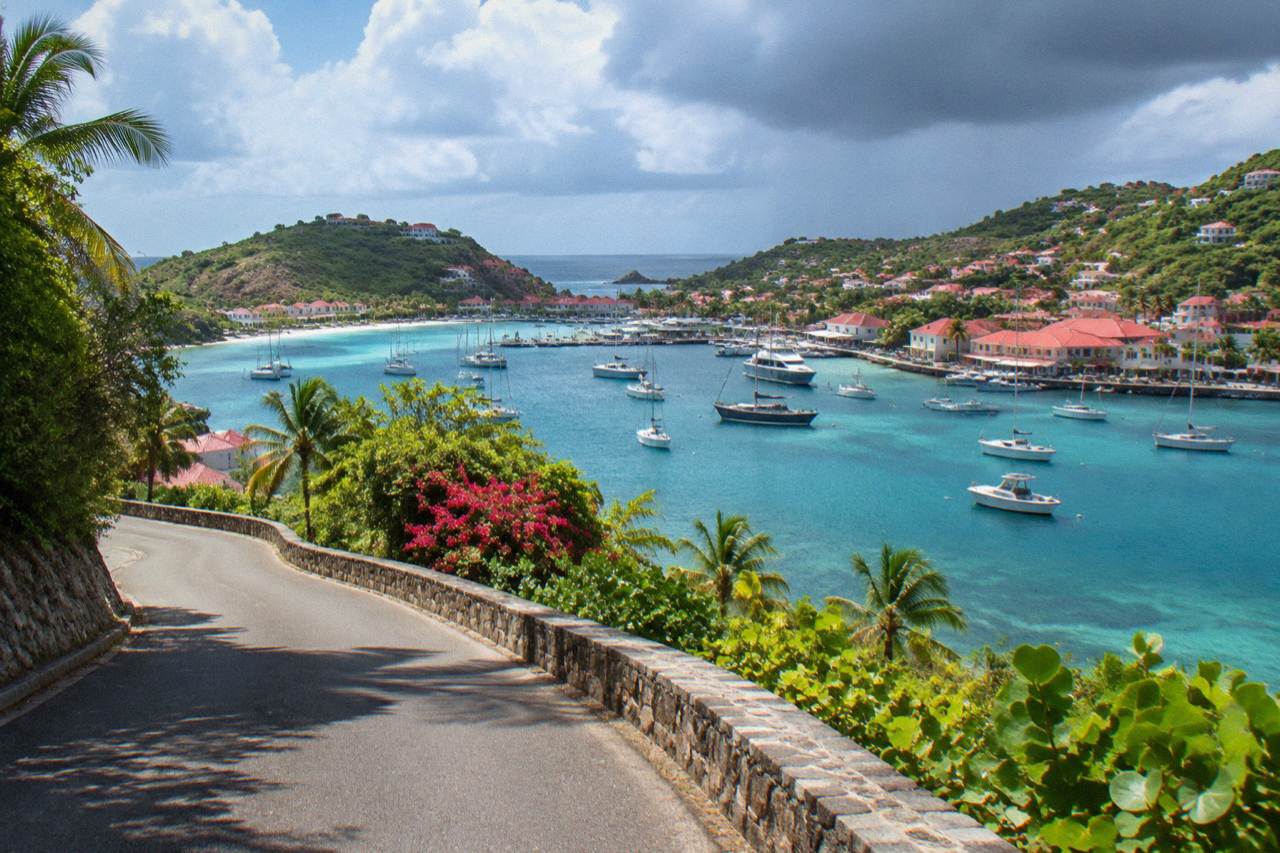 An empty hillside road above a turquoise Caribbean bay on St Barts in soft morning light