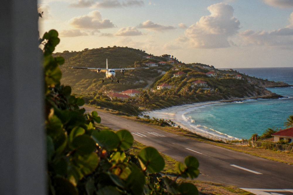 A small turboprop aircraft on a short runway beside a Caribbean beach