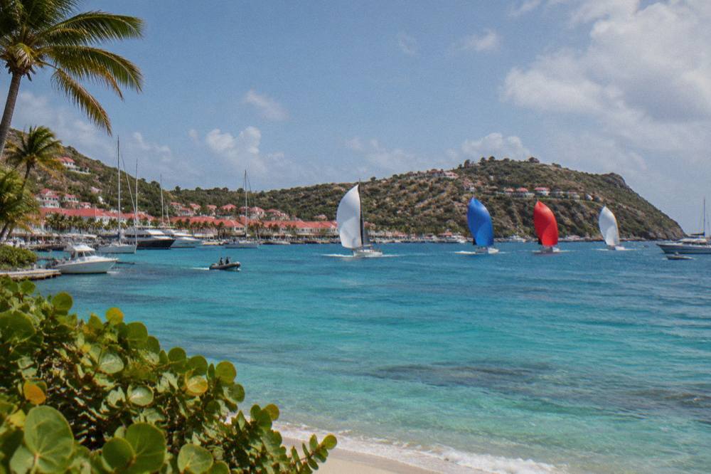 Racing yachts with spinnakers flying across a bay in St Barts