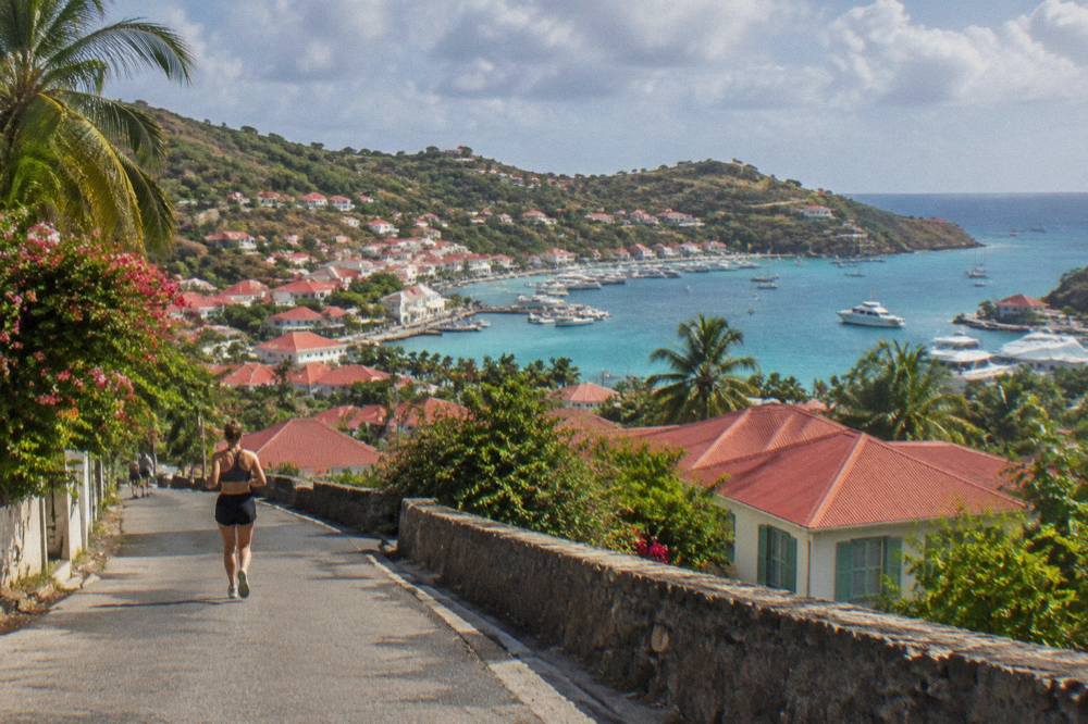 Red roofs of Gustavia seen from a hillside road under scattered clouds