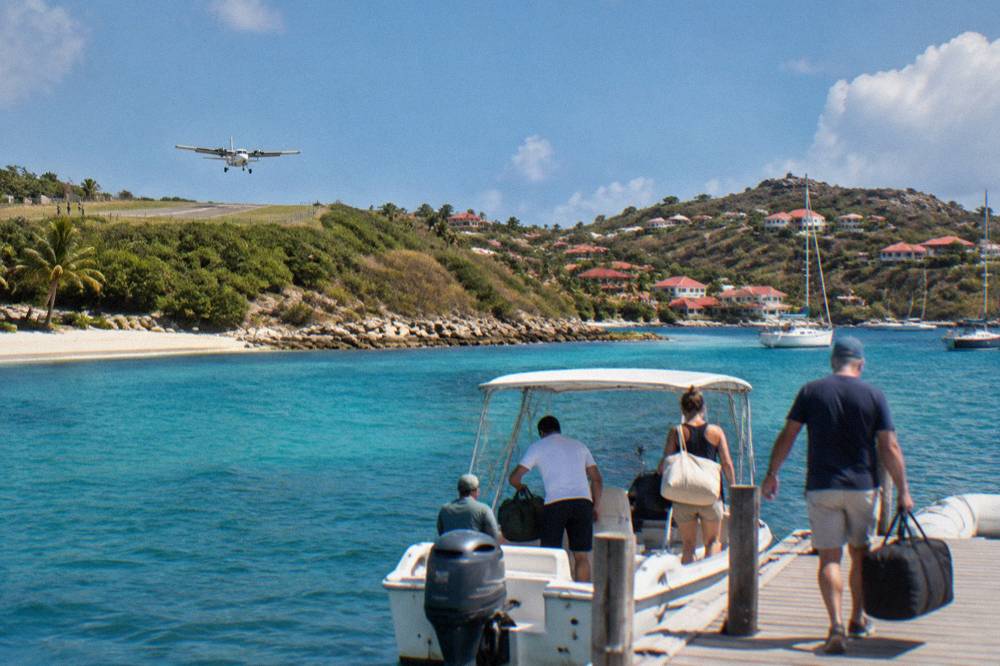 Travelers lifting soft duffel bags onto a small boat at a Caribbean marina dock