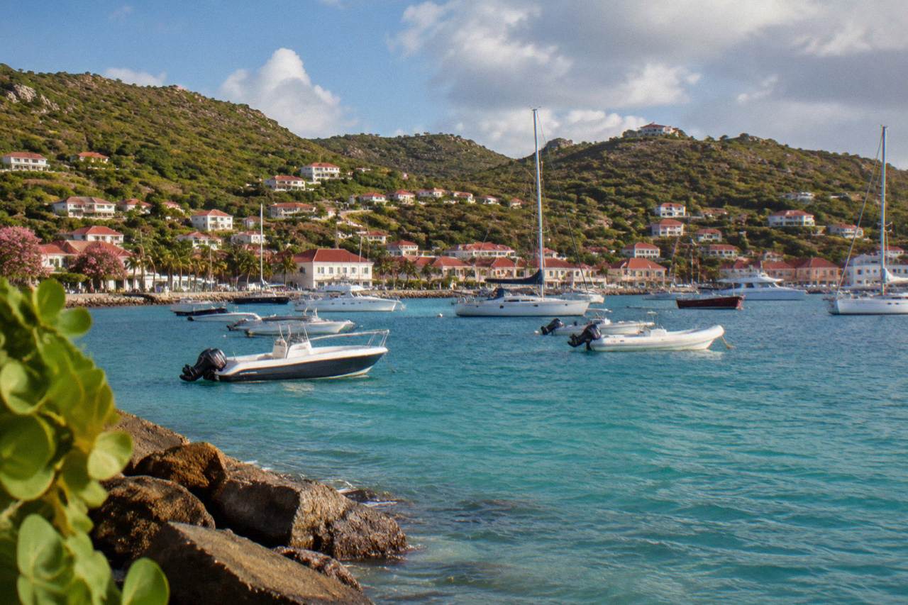 View over turquoise water toward a green Caribbean island with white buildings along a harbour