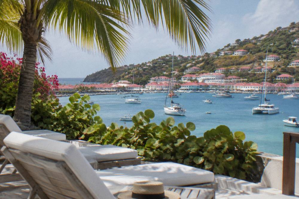 Terrace with white loungers and palm shade looking out to a calm blue bay