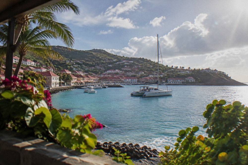 Sailing catamaran anchored in a quiet bay with a wooded headland behind it