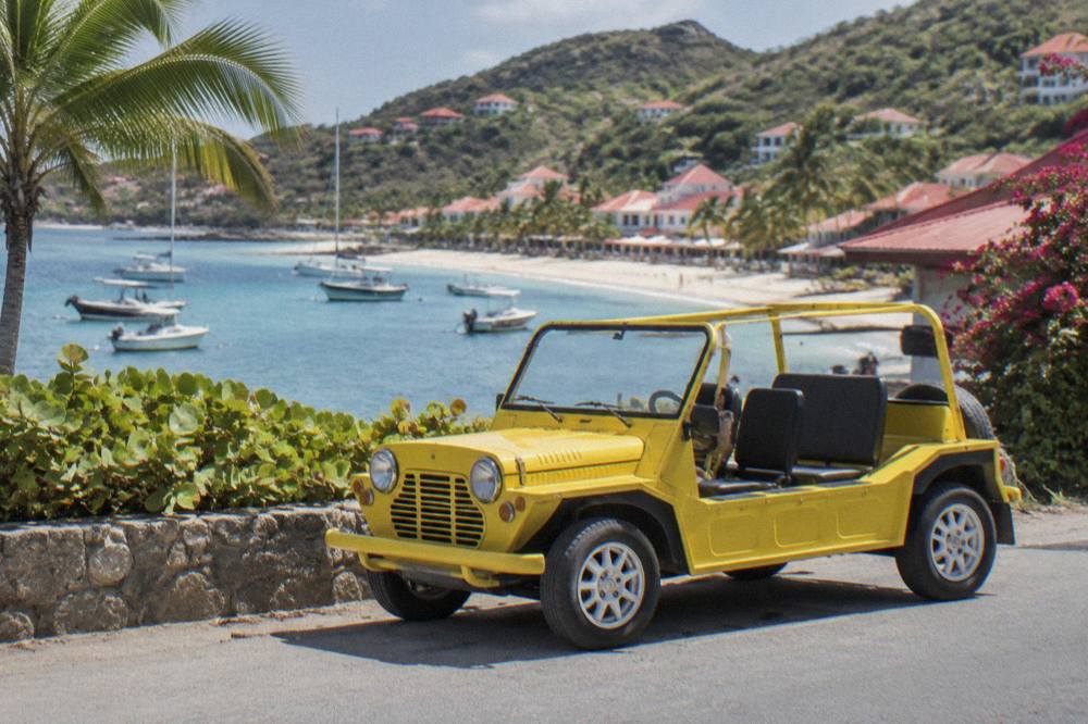 Close view of a brightly colored open-top Mini Moke with its simple interior and no side windows
