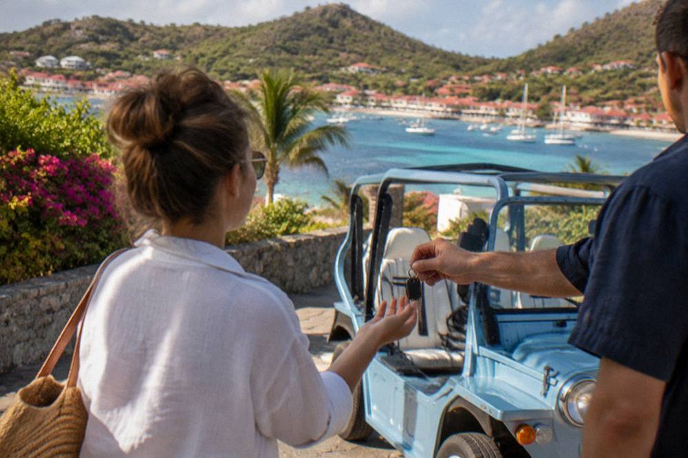 A traveler handing over keys beside a Mini Moke at a villa driveway in warm evening light