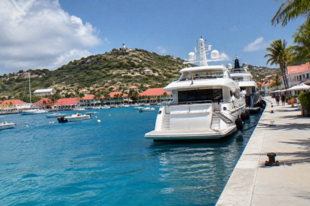 Superyachts moored stern-to along a quay in a small Caribbean harbour town