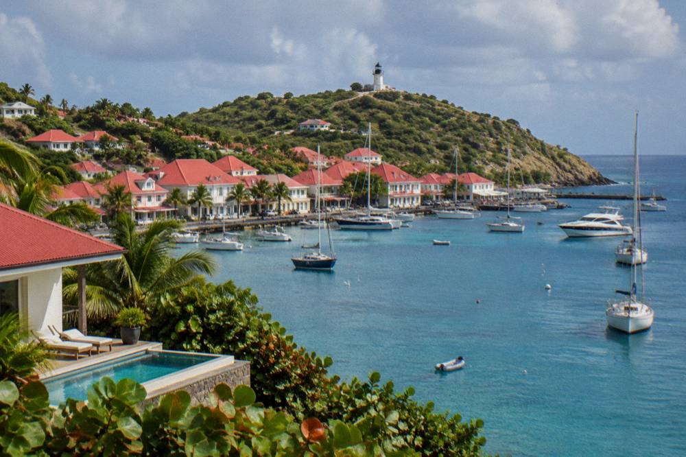 A hillside villa with a pool overlooking the sea and a distant harbour town