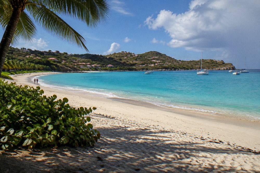 Sunlit hills above a curved bay with turquoise shallows
