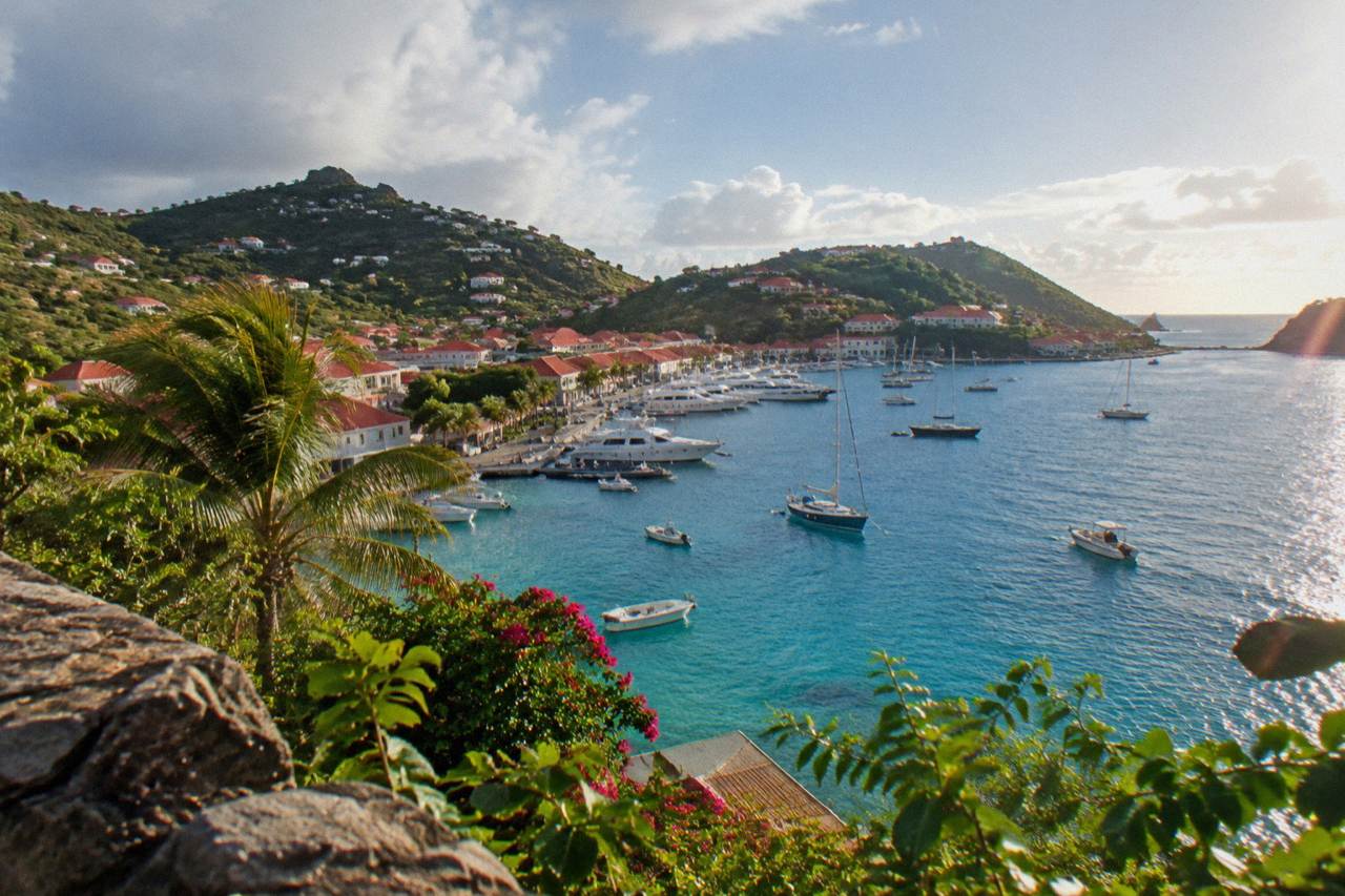 A view over turquoise water toward green hills and red rooftops on a Caribbean island