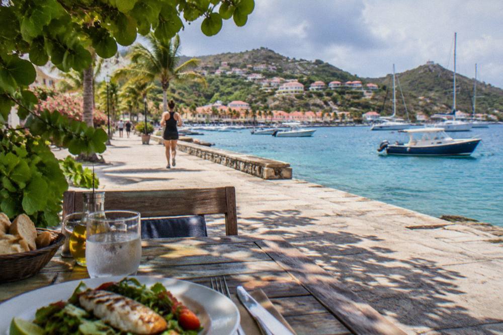 A shaded outdoor table with a simple lunch laid out beside the sea