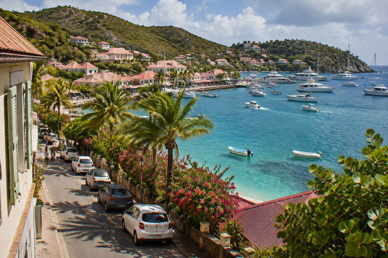 A narrow street in Gustavia with small cars parked along the harbour side on St Barts