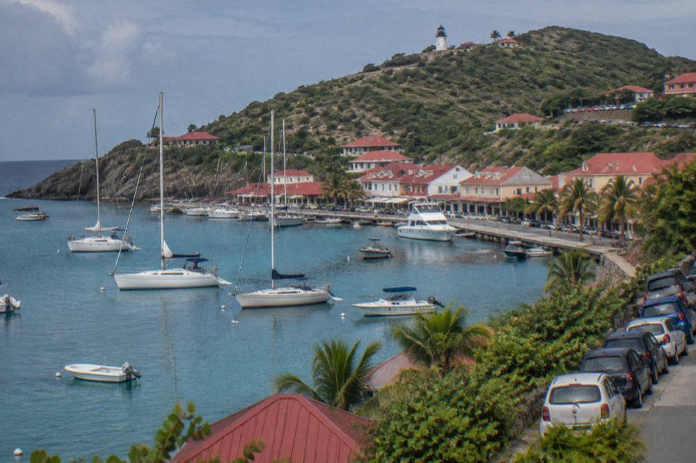 Small rental cars parked close together on a hillside road above Gustavia harbour