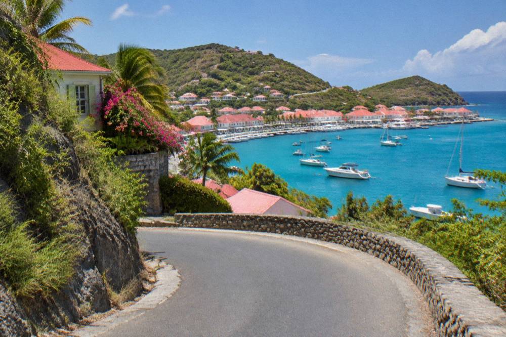 A steep narrow road with a sharp bend between hillsides on St Barts