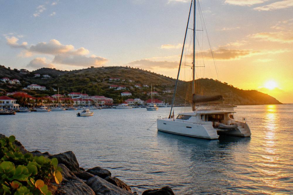 A catamaran moored in a quiet bay at sunset near St Barts