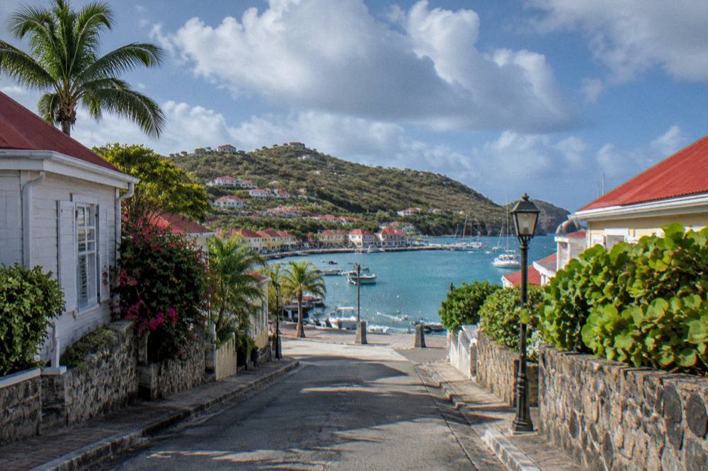 An empty narrow street in Gustavia in early morning light with the harbour beyond