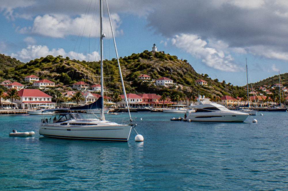 Gustavia harbor seen from the water with yachts at anchor and red roofs on the hillside
