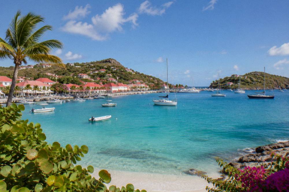 Sailboats anchored in turquoise water off a green headland in St Barts
