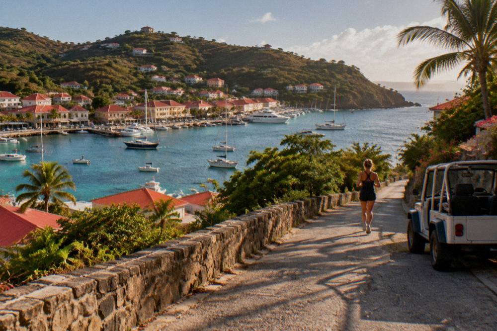 A small open-sided rental car parked on a narrow hillside road above the sea in St Barts