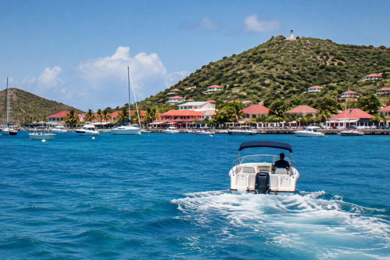 A private motorboat crossing open Caribbean water toward green hills on the horizon