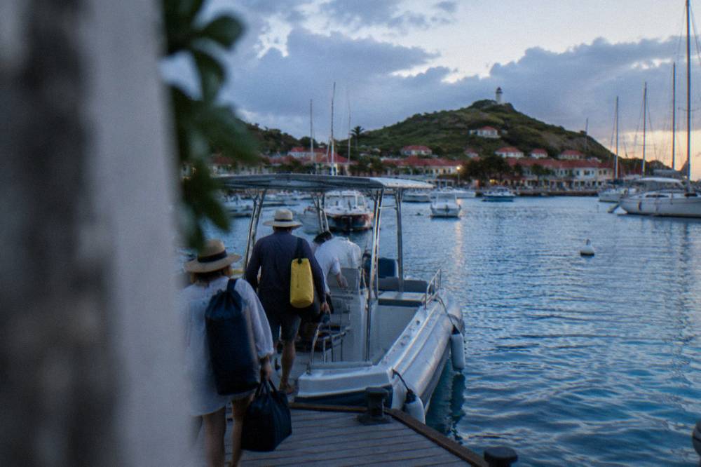 Passengers in dry bags and sun hats boarding a charter boat at a marina pontoon