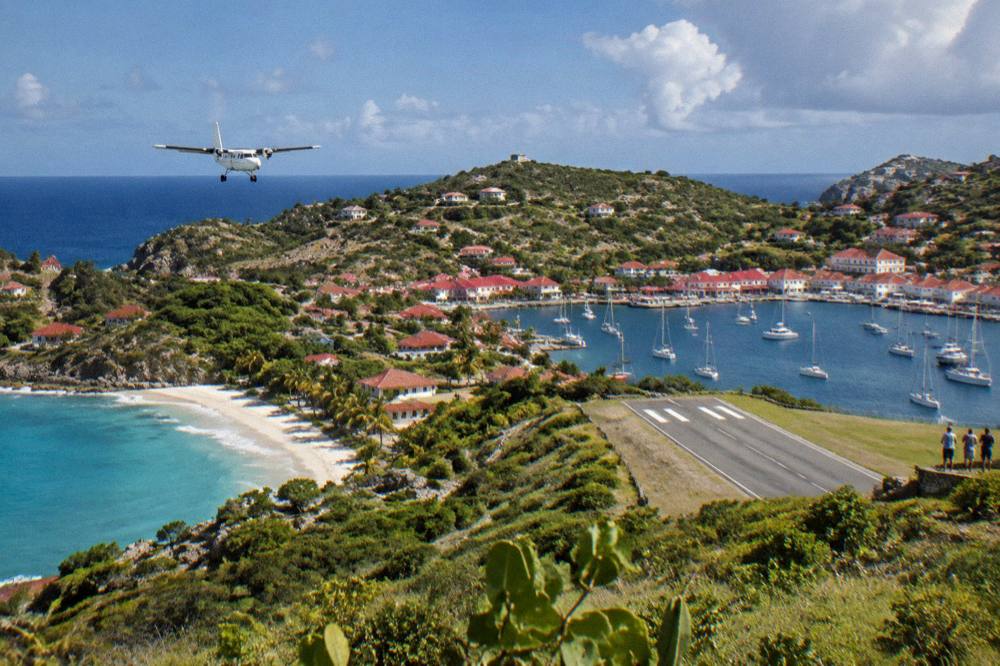Red-roofed Caribbean harbor buildings along a waterfront filled with masts